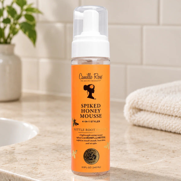 Camille Rose Spiked Honey Mousse 4 in 1 Styler Define, Hydrate & Style for Curly & Textured Hair — 8 oz on a bathroom vanity.