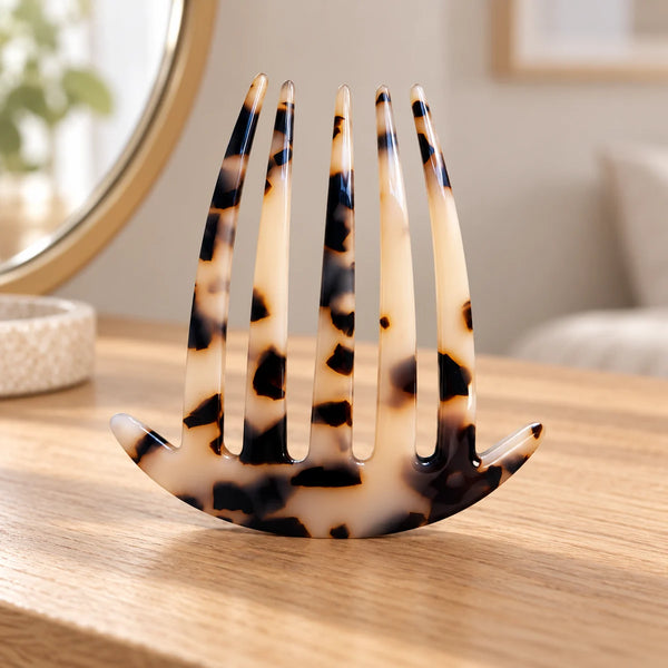 Tortoiseshell acetate clip comb on a wooden dressing table.