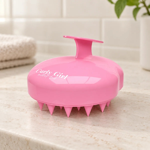 Pink scalp massager on a bathroom vanity.