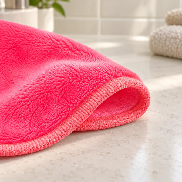 Pink microfibre hair drying cloth on a bathroom vanity.