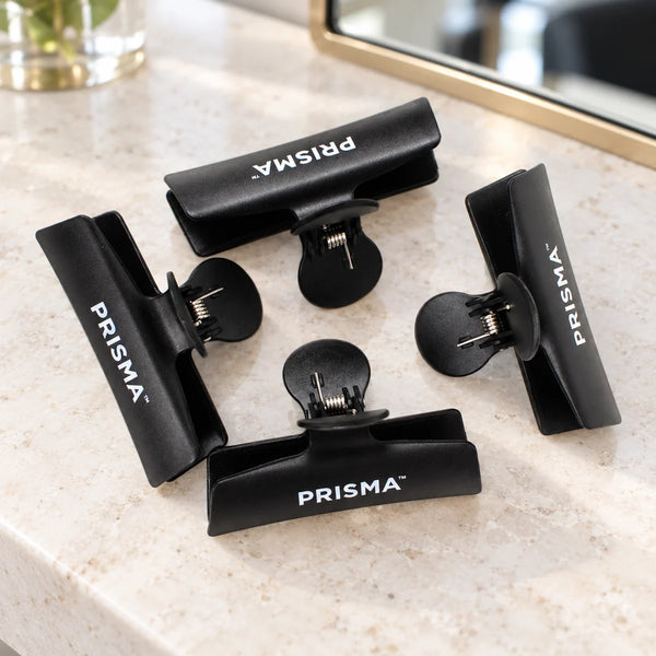 Prisma Black Butterfly Sectioning Clips — Pack of 4 — Four black Prisma butterfly sectioning clips on a salon counter.