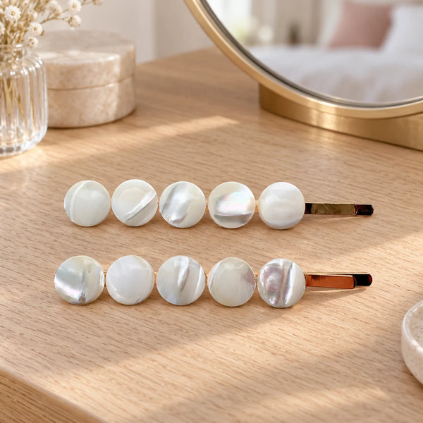 Reverie Hair Seaside Romance Hair Pins — Two Pebble-style seashell hair slides on a dressing table.