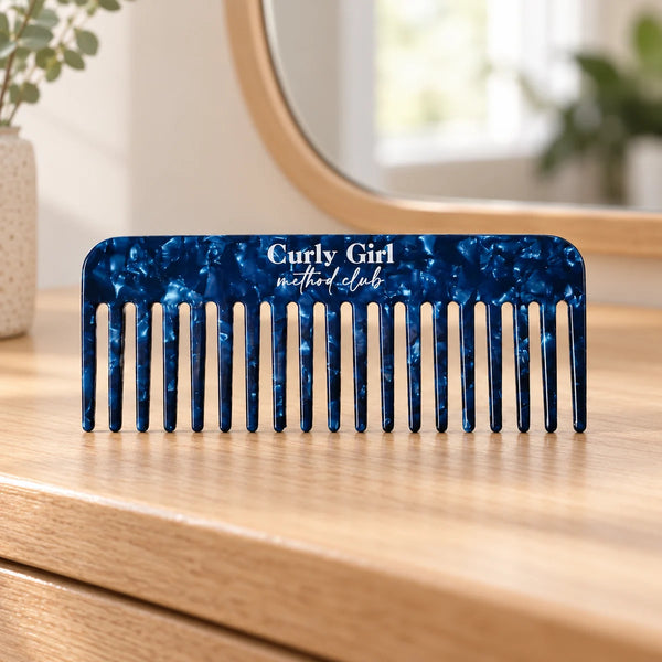Blue acetate wide-tooth comb on a wooden dressing table.