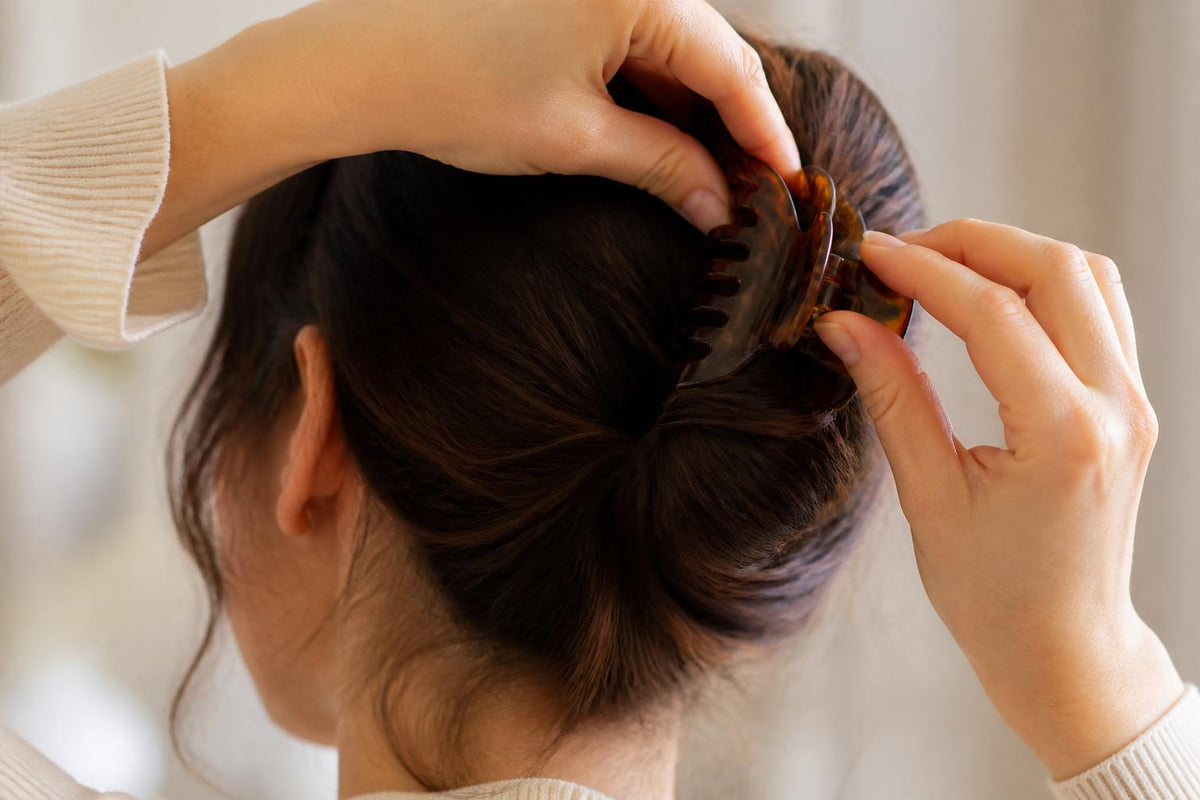 A collection of gold hair clips, silk scrunchies, and claw clips arranged neatly on a soft beige surface