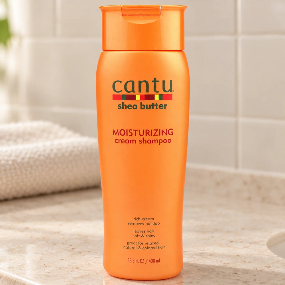 Cantu Shea Butter Moisturizing Cream Shampoo Deeply Hydrates & Cleanses for Natural & Textured Hair — 400 ml on a bathroom vanity.