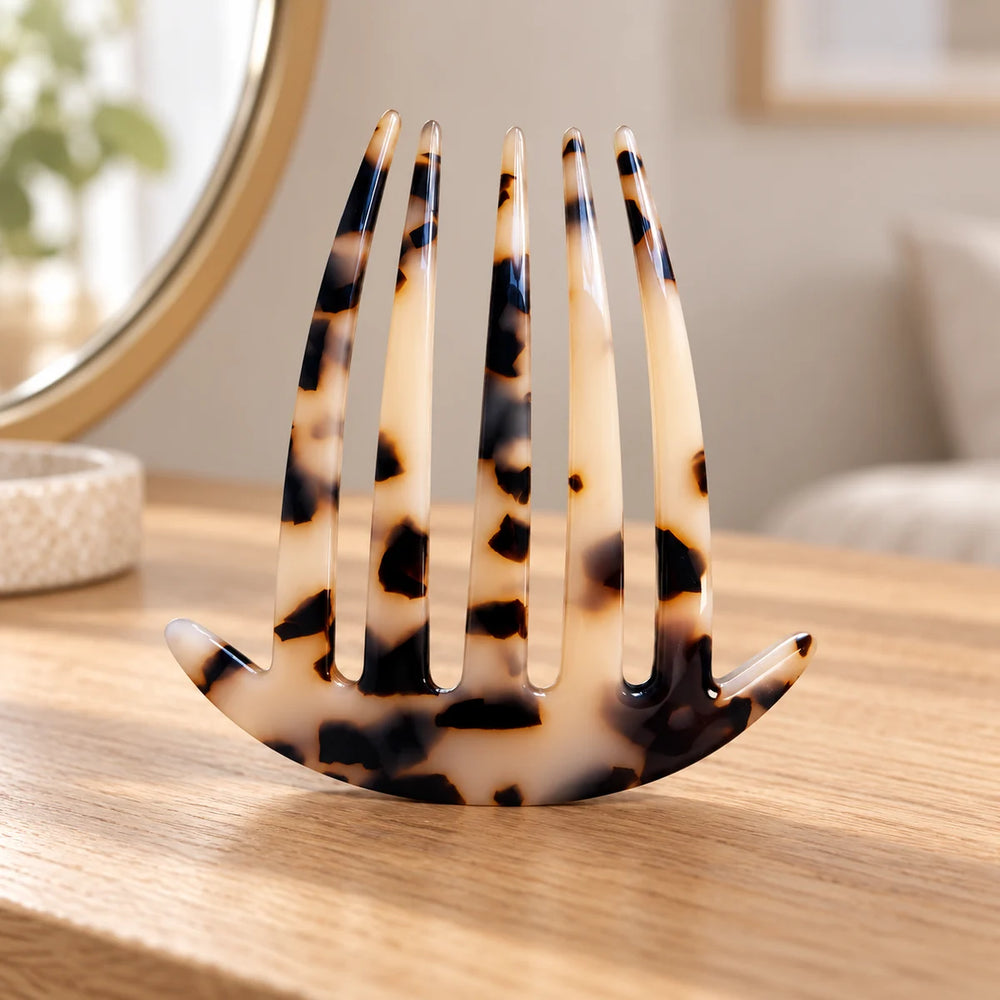 Tortoiseshell acetate clip comb on a wooden dressing table.
