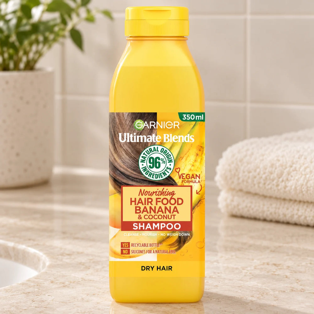 Garnier Hair Food Banana & Coconut Shampoo: Nourishing & Restoring for Dry, Frizzy Hair — 350 ml on a bathroom vanity.