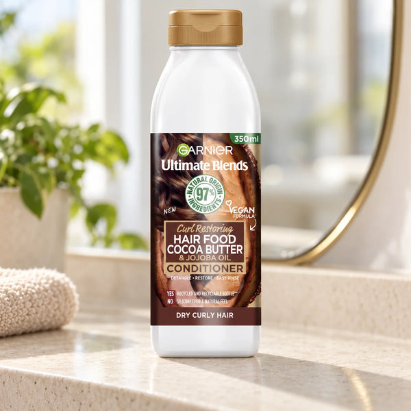 Garnier Hair Food Cocoa Butter & Jojoba Oil Conditioner Deeply Nourishing & Repairing for Dry, Frizzy & Damaged Hair — 350 ml on a bathroom vanity.
