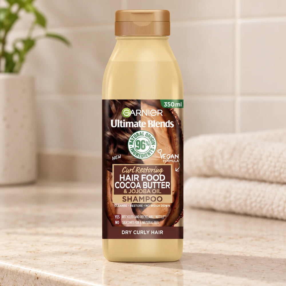 Garnier Hair Food Cocoa Butter & Jojoba Oil Shampoo: Nourishing & Repairing for Dry, Damaged Hair — 350 ml on a bathroom vanity.