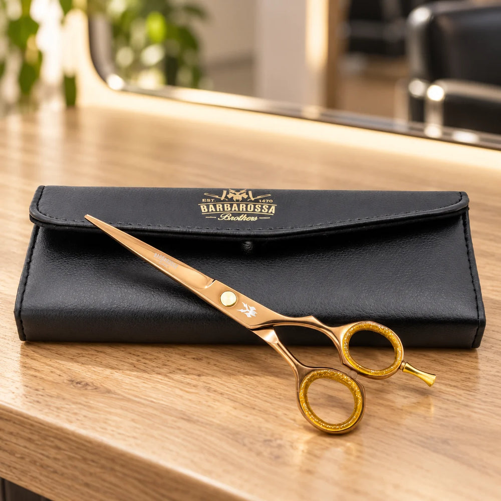 Barbarossa rose-gold cutting scissors with case on a salon worktop.