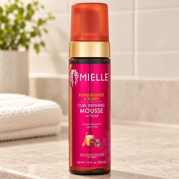 Mielle Pomegranate & Honey Curl Defining Mousse — 7.5 oz on a bathroom vanity.