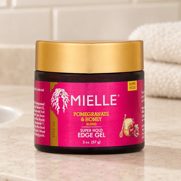 Mielle Pomegranate & Honey Super Hold Edge Gel — 2 oz on a bathroom vanity.