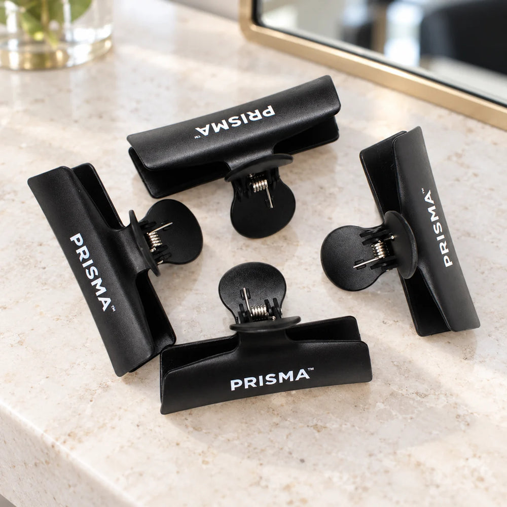 Prisma Black Butterfly Sectioning Clips — Pack of 4 — Four black Prisma butterfly sectioning clips on a salon counter.