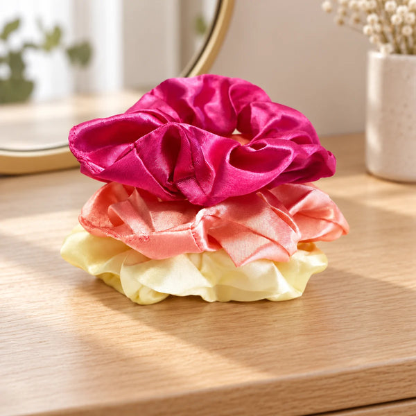 Set of three satin scrunchies on a wooden dressing table.
