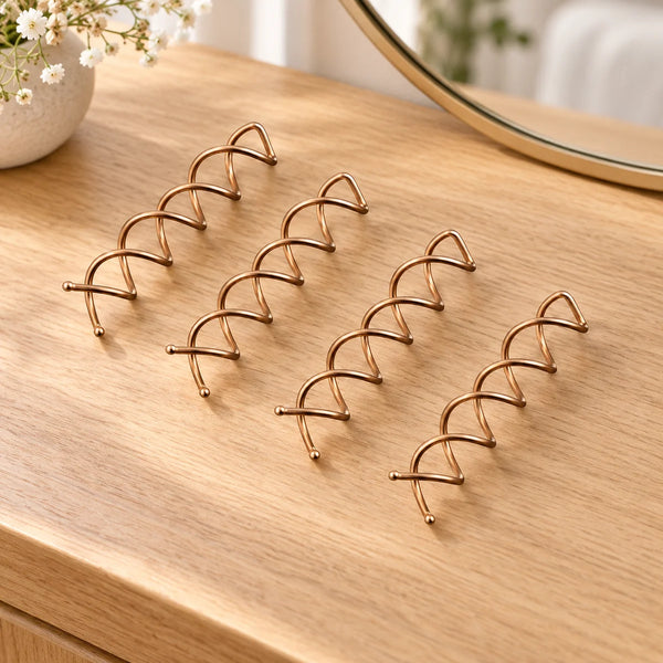 Four bronze twist hair pins on a wooden dressing table.