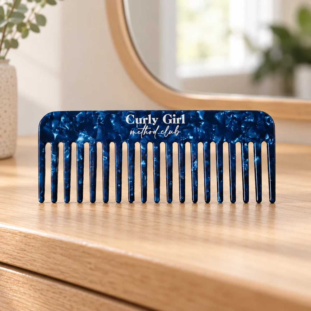 Blue acetate wide-tooth comb on a wooden dressing table.